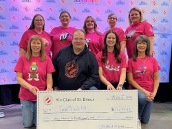 members of the Kin Club, wearing pink t-shirts and standing in a group photo holding a giant cheque